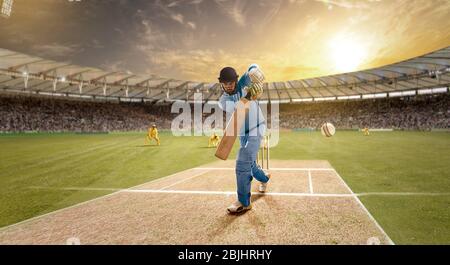 Der junge Sportler schlägt den Ball beim Schlagstock auf dem Cricket-Feld Stockfoto