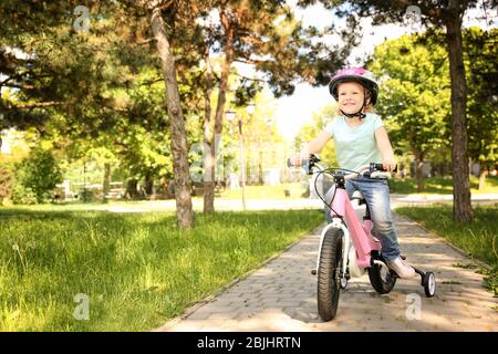 Nettes kleines Mädchen Fahrrad im Park an sonnigen Tag fahren Stockfoto