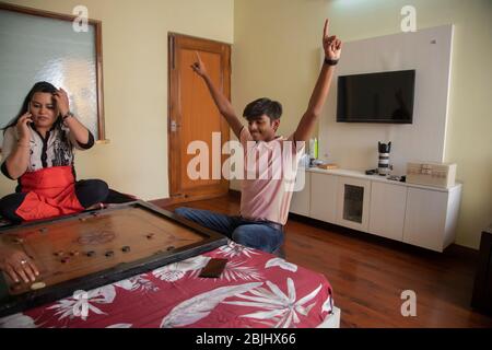 Sohn spielt mit seiner Mutter zu Hause Carrom-Board. Stockfoto