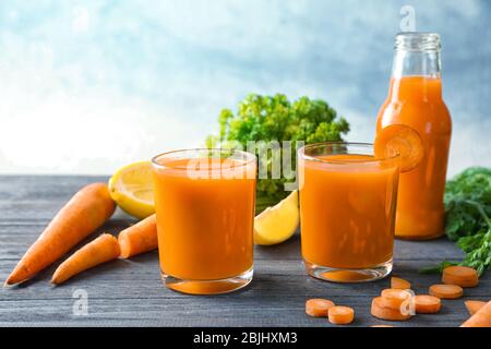 Gläser selbstgemachter Karottensaft mit Gemüse auf dunklem Holztisch Stockfoto