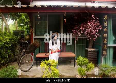 RATCHABURI, THAILAND - SEPTEMBER 24 : Reisende thai Frauen tragen Kleidung vietnamesischen ethnischen Stil mit Bambushut und roten Regenschirm für Foto in gar zu machen Stockfoto