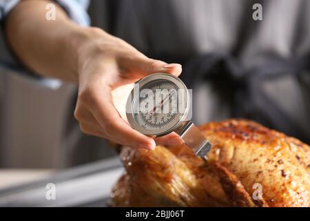 Junge Frau Messung der Temperatur der ganzen gerösteten pute mit Fleisch-Thermometer Stockfoto
