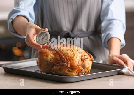 Junge Frau Messung der Temperatur der ganzen gerösteten pute mit Fleisch-Thermometer Stockfoto