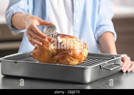 Junge Frau Messung der Temperatur der ganzen gerösteten pute mit Fleisch-Thermometer Stockfoto