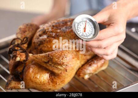 Junge Frau Messung der Temperatur der ganzen gerösteten pute mit Fleisch-Thermometer Stockfoto