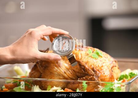 Junge Frau Messung der Temperatur der ganzen gerösteten pute mit Fleisch-Thermometer Stockfoto