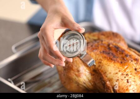 Junge Frau Messung der Temperatur der ganzen gerösteten pute mit Fleisch-Thermometer Stockfoto