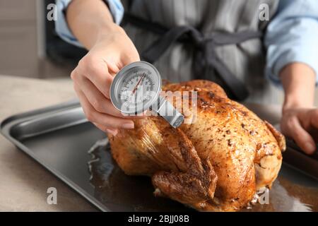 Junge Frau Messung der Temperatur der ganzen gerösteten pute mit Fleisch-Thermometer Stockfoto