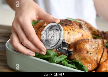 Junge Frau Messung der Temperatur der ganzen gerösteten pute mit Fleisch-Thermometer Stockfoto