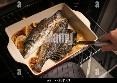 Frau, die Fisch im Ofen kocht Stockfoto