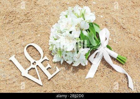 Schöner Strauß und WORTLIEBE auf Sand. Hochzeitskonzept am Strand Stockfoto