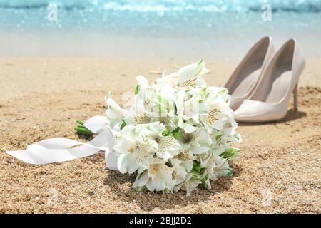 Schöner Bouquet und hohe Absatz Schuhe auf Sand. Hochzeitskonzept am Strand Stockfoto