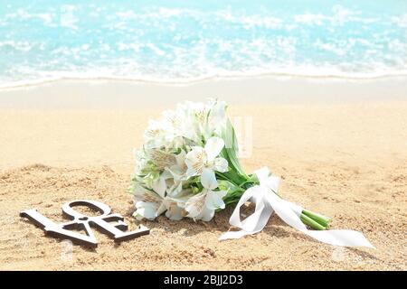 Schöner Strauß und WORTLIEBE auf Sand. Hochzeitskonzept am Strand Stockfoto