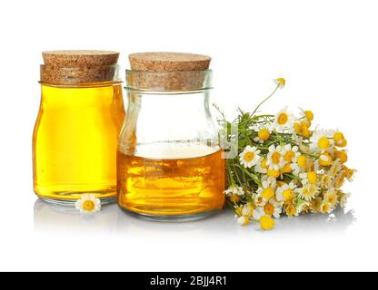 Gläser mit ätherischem Öl und Kamillenblüten auf weißem Hintergrund Stockfoto