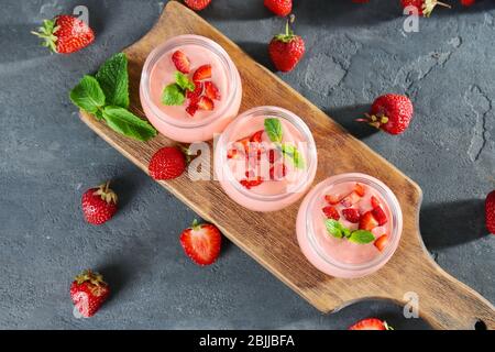 Köstliche hausgemachte Joghurt mit Erdbeere in Gläsern auf grauem Hintergrund Stockfoto