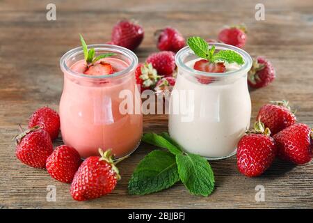 Gläser mit köstlichem hausgemachten Joghurt und Erdbeere auf Holztisch Stockfoto