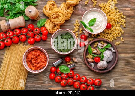 Zusammensetzung mit Pesto, Bolognese und weißen Saucen für Pasta in Schüsseln auf dem Tisch Stockfoto