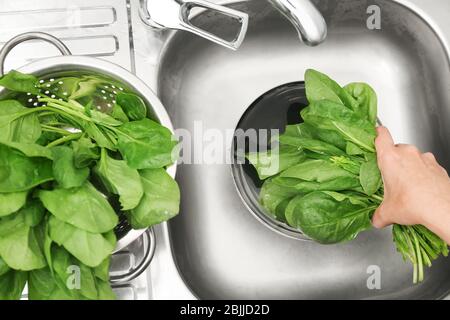 Frau, die Spinat im Waschbecken spüle Stockfoto