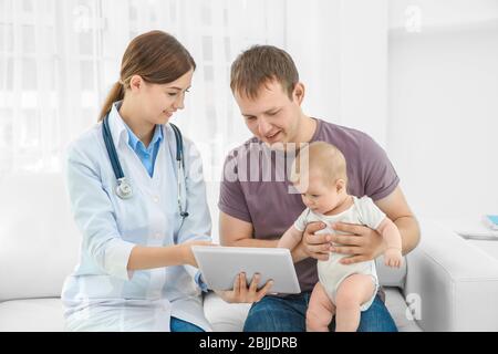 Arzt zeigt Vater ein Ergebnis der Untersuchung auf dem Tablet im Krankenhaus Stockfoto