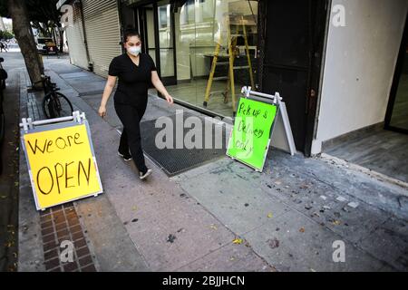 Los Angeles, Usa. April 2020. Ein Fußgänger geht an Schildern vorbei, während er eine Gesichtsmaske als Schutzmaßnahme während der Sperrung inmitten des Coronavirus trägt.das US-Gesundheitsministerium verzeichnete insgesamt 1.06M Infektionen, Todesfälle 61,361 und 123 erholten sich seit Beginn des Ausbruchs. Quelle: SOPA Images Limited/Alamy Live News Stockfoto