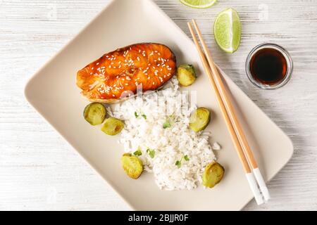 Fischsteak mit Reis und Sojasoße auf Holzuntergrund serviert Stockfoto