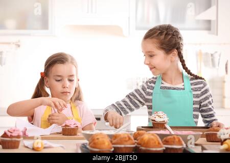 Nette Mädchen dekorieren Cupcakes in der Küche während Kochkurse Stockfoto