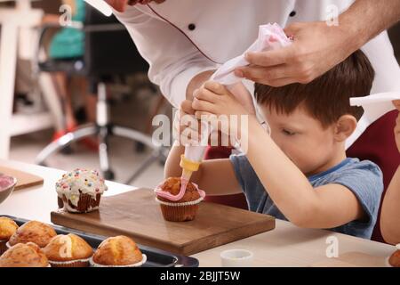 Lehrer helfen Jungen Cupcake während Kochkurse schmücken Stockfoto