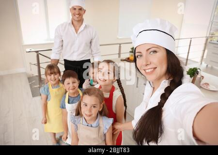 Zwei Köche und süße Kinder machen Selfie nach dem Kochkurs Stockfoto