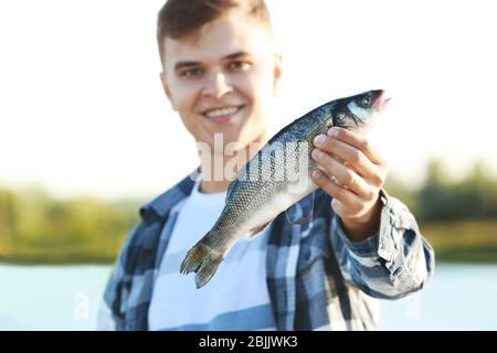 Junger Mann hält frisch gefangenen Fisch Stockfoto