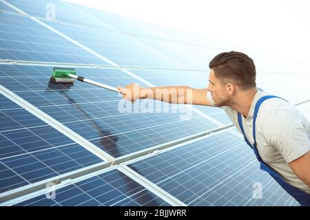 Junger Arbeiter Waschen Solarzellen nach der Installation im Freien Stockfoto