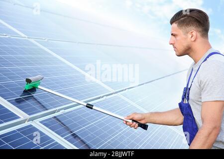 Junger Arbeiter Waschen Solarzellen nach der Installation im Freien Stockfoto