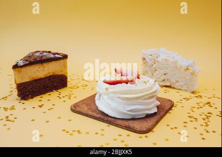 Drei verschiedene Arten von Süßigkeiten Kuchen auf einem gelben Hintergrund mit goldenen Pailletten Stockfoto