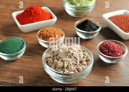 Verschiedene bunte Superfood Pulver in Schalen auf Holztisch Stockfoto