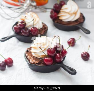 Mini-Torten in Eisenkernen mit Oreo-Keksteig, Schokoladenfüllung, Schlagsahne und frischen Beeren. Stockfoto