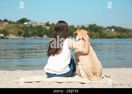 Junge Frau mit gelbem Retriever in der Nähe des Flusses ausgeruht Stockfoto