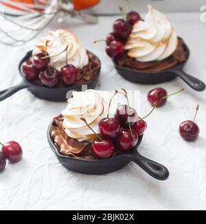 Mini-Torten in Eisenkernen mit Oreo-Keksteig, Schokoladenfüllung, Schlagsahne und frischen Beeren. Stockfoto