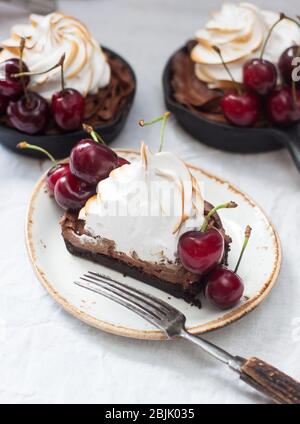 Mini-Torten in Eisenkernen mit Oreo-Keksteig, Schokoladenfüllung, Schlagsahne und frischen Beeren. Stockfoto