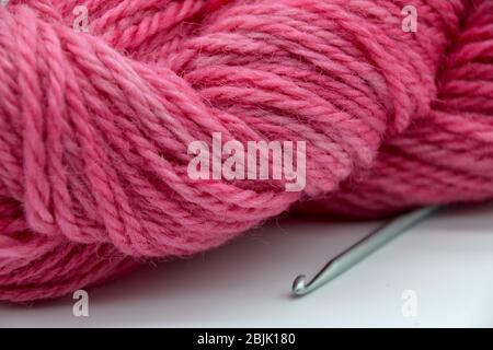 Nahaufnahme Makro Studio Aufnahme von einem Ball oder skein aus rosa Wolle Garn mit Metall Häkelnadel Stockfoto