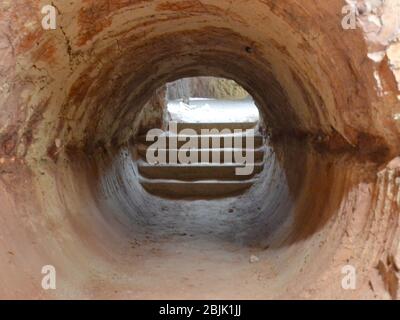 Sandsteinfelsen-Tunnel mit Stufen, die draußen zum Tageslicht führen in einer alten Opalmine in Coober Pedy in Australien Stockfoto