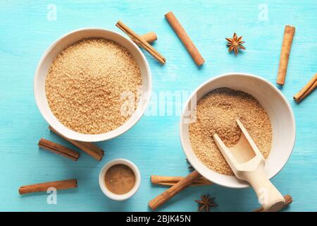 Süßer Zimtzucker in Schalen auf farbigem Holztisch Stockfoto