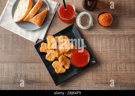 Komposition mit Hähnchennuggets und Chilisauce auf Küchentisch Stockfoto