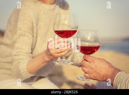 Glückliches älteres Paar, das Wein auf dem Meer trinkt, Nahaufnahme Stockfoto