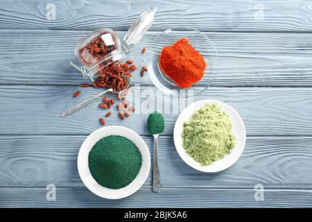 Verschiedene bunte Superfood Pulver in Geschirr auf Holzhintergrund Stockfoto