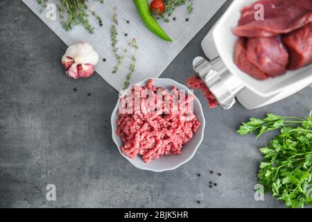 Fleischmühle mit frischem Zangenfleisch auf Küchentisch Stockfoto