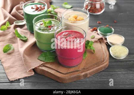 Gläser mit verschiedenen Smoothies auf Holzbrett Stockfoto