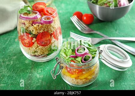 Zusammensetzung mit Quinoa und Gemüse in Glaswaren auf dem Tisch Stockfoto