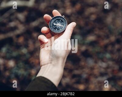 Weibliche Hand mit Kompass auf Hintergrund des Waldes, Standpunkt Stockfoto