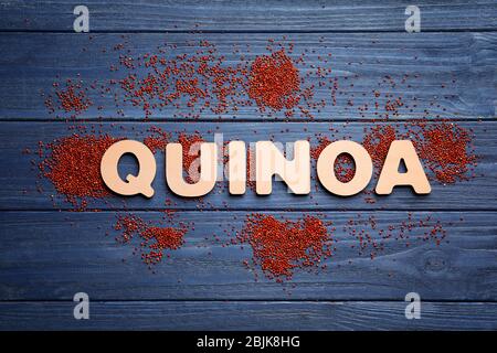 Wort QUINOA aus Holzbuchstaben und Samen auf dem Tisch Stockfoto