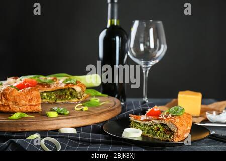 Leckere Torte mit Spinat zum Abendessen auf dem Tisch vor schwarzem Hintergrund serviert Stockfoto