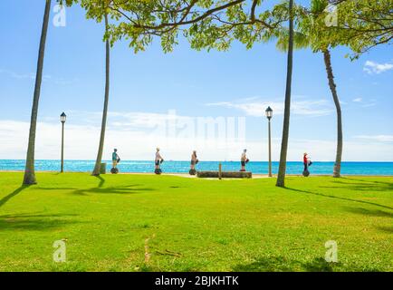 Gruppe von 5 Touristen, die an einem sonnigen Tag selbstbalancierende Motorroller entlang des Spazierwegs am Meer in Waikiki, Honolulu, Hawaii reiten Stockfoto